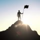 Man standing on top of hill with flag
